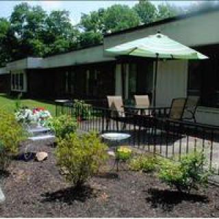 A patio area with outdoor furniture and a large umbrella, surrounded by landscaped gardens.