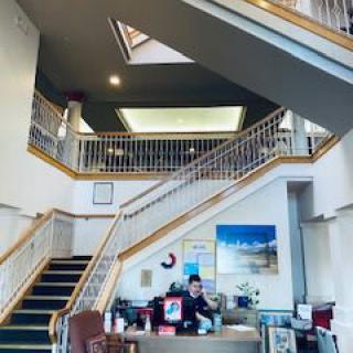 A spacious office building interior with a reception desk and a grand staircase.