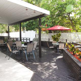 An inviting outdoor patio area with seating, plants, and an umbrella for shade.