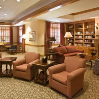 A cozy living room with comfortable chairs, a sofa, and bookshelves filled with books.