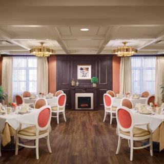 An elegant dining room interior with neatly arranged tables and chairs, featuring classic decor and chandeliers.