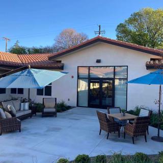 A modern outdoor patio area with comfortable seating and umbrellas, set against a bright blue sky.