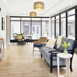A modern and bright living room with large windows, comfortable seating, and a dining area.