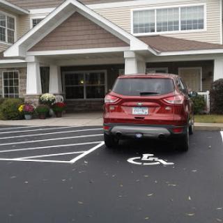 A red SUV parked in a handicap spot in front of a residential building.
