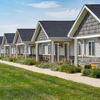 A row of similar styled suburban houses with well-maintained lawns and a sidewalk.