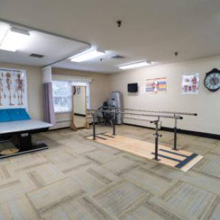 A spacious physical therapy room equipped with exercise equipment and ballet bars for rehabilitation.
