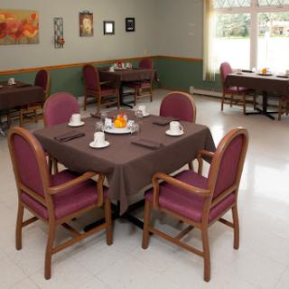 A cozy dining room setup featuring a brown table with chairs, ready for guests.
