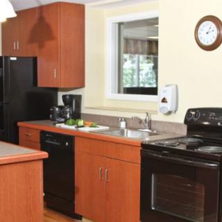 A modern kitchen featuring wooden cabinets, a black refrigerator and stove, a sink, and various kitchen appliances.