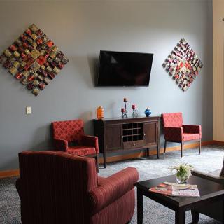 A cozy living room with modern artwork, a television mounted on the wall, and comfortable seating.