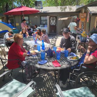 A lively outdoor gathering with friends enjoying a meal together under the sun.