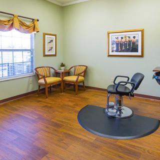 A well-lit hair salon with a barber chair and a small waiting area.