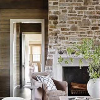 A stylish living room featuring a rustic stone wall and a cozy fireplace, blending modern design with comfort.