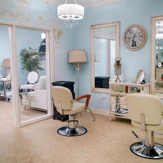 A stylish and elegantly furnished hair salon with light blue walls and chic decor.