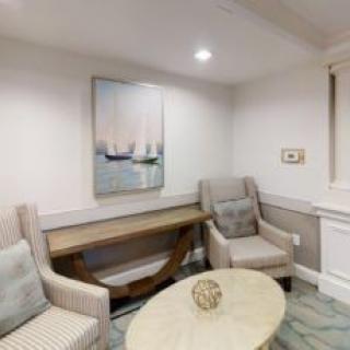 A cozy living room with modern furniture and nautical-themed artwork.