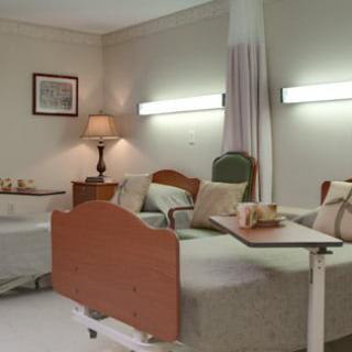 A well-furnished hospital room with two beds and a comfortable seating area.