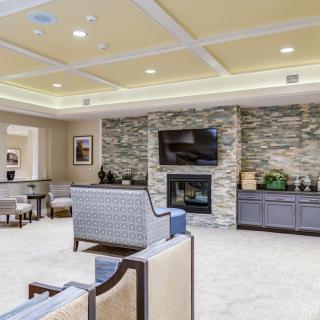 A modern living room featuring a stone fireplace, comfortable seating, and a large television.