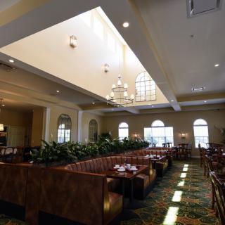 A spacious restaurant interior featuring booths, chandeliers, and natural light from ceiling windows.