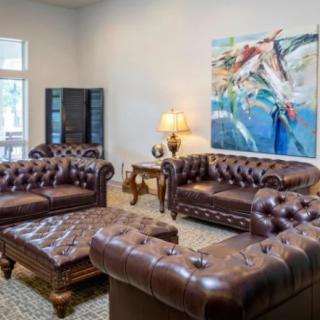 A stylish living room with leather couches and colorful artwork on the wall.