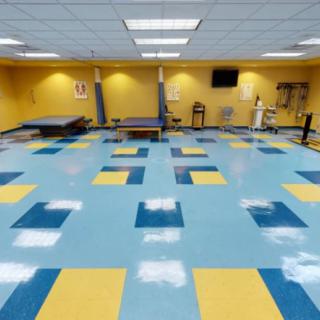 A spacious gym with exercise equipment and colorful flooring.