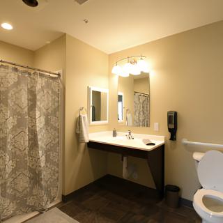 A modern bathroom with a shower, sink, and toilet.