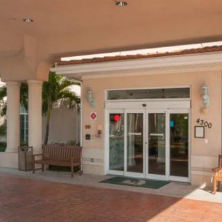 The entrance of a hotel with glass doors and outdoor seating.