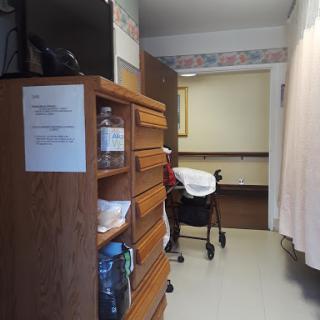 A glimpse into a patient room showcasing wooden furniture and a wheelchair.