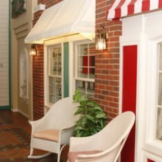 A cozy indoor setting with two chairs next to brick walls and windows, adorned with an awning and greenery.