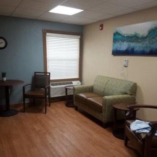 A cozy waiting room with a sofa, chairs, and artwork on the wall.