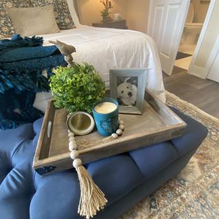 A cozy bedroom setup featuring a decorative tray with a plant, candle, and photo frame.
