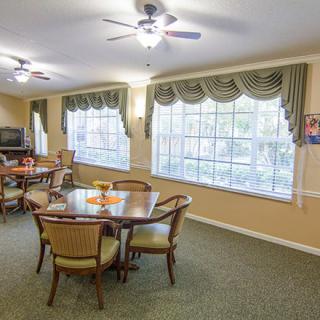 A cozy living room with a dining area, featuring large windows and elegant furnishings.