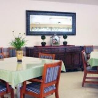 A cozy dining area with tables and chairs, decorated with plants and a large framed mirror.