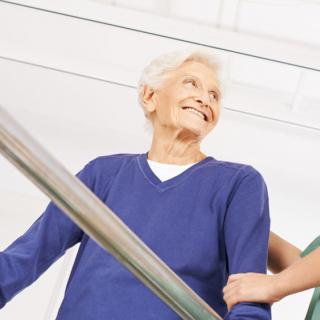 An elderly woman receiving assistance from a caregiver while navigating stairs.
