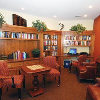 A cozy library with bookshelves, comfortable chairs, and a small table.