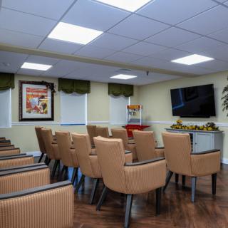 A well-arranged conference room with rows of chairs facing a large television and artwork on the wall.