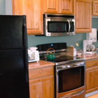 A modern kitchen with wooden cabinets, a black refrigerator, and stainless steel appliances.