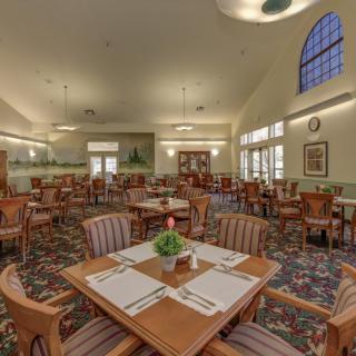 A spacious dining area with neatly arranged tables and chairs, featuring large windows and elegant decor.