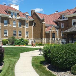 A large residential building with a well-maintained lawn and garden on a sunny day.