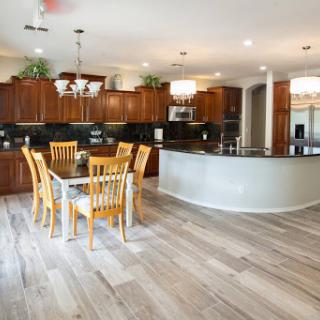 A spacious and modern kitchen featuring a dining area with wooden chairs and an elegant chandelier.