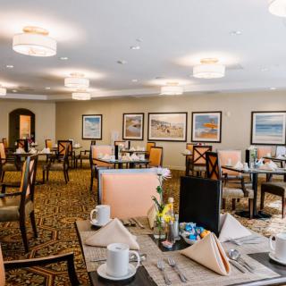 A neatly arranged dining area with tables and chairs, decorated with artwork and soft lighting.