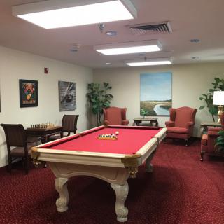 A cozy game room featuring a red pool table surrounded by comfortable seating and artwork.