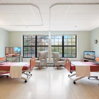 A clean and spacious hospital room with two beds and large windows.