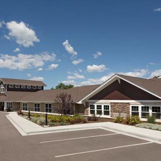 A residential building with a parking lot under a beautiful blue sky with clouds.