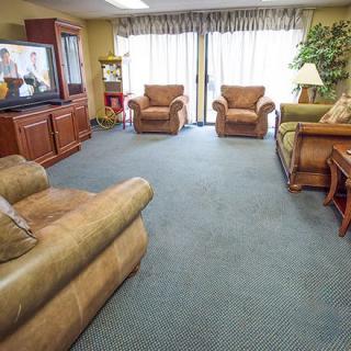 A cozy living room with multiple armchairs, a sofa, a television, and a large window with curtains.