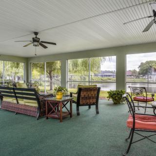 A cozy screened porch with outdoor furniture overlooking a lake.