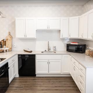 A modern kitchen with white cabinets and dark appliances.