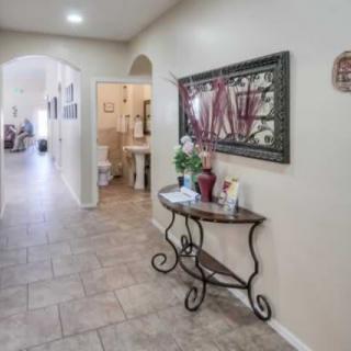 A well-decorated hallway with tile flooring, featuring a console table and artwork on the wall.