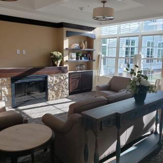 A cozy living room with ample natural light, featuring a sofa, coffee table, and a fireplace.