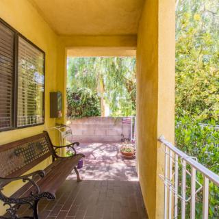 A charming porch with a garden view featuring a wooden bench and yellow walls.
