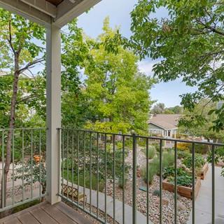A scenic view from a balcony overlooking a lush garden and trees.
