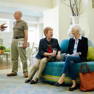 A group of seniors engaging in conversation in a bright, indoor setting.